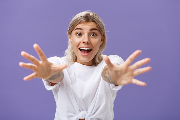 Taillenschuss der amüsierten und aufgeregten attraktiven stilvollen jungen Frau im weißen T-Shirt