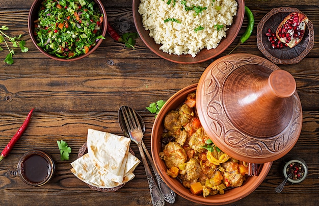 Tajine platos tradicionales, cuscús y ensalada fresca en la mesa de madera rústica. Tagine de carne de cordero y calabaza. Vista superior. Lay Flat