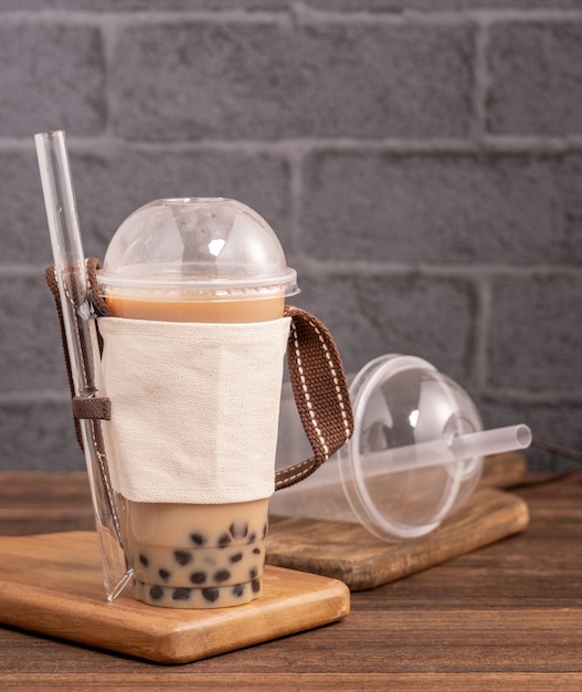 Take-out mit Einwegartikel Konzept beliebte Taiwan trinken Bubble Milk Tee mit Plastikbecher und Stroh auf Holztisch