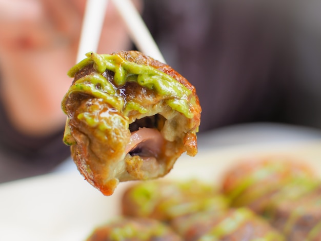 Takoyaki com o bolinho de massa japonês do molho e do polvo de chá verde. Cidade de Uji, Kyoto, Japão