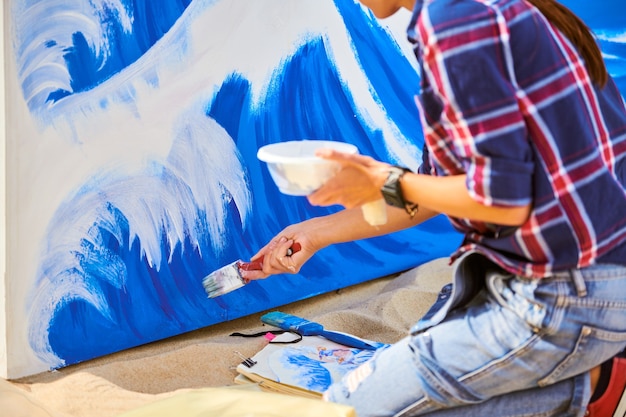 Talentosa artista feminina pintando em tela de madeira, trabalhando em uma pintura a óleo abstrata moderna no festival, gesticulando com pinceladas largas. Belas artes, criatividade e conceito de pessoas