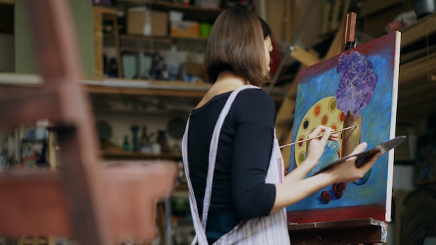 Foto talentosa joven artista pintando un cuadro sobre lienzo en clase de arte