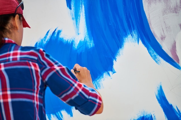 Talentoso artista femenino pintando sobre lienzo de madera trabajando en pintura al óleo abstracta moderna en el festival, gesticulando con trazos amplios con pincel. Concepto de bellas artes, creatividad y personas.