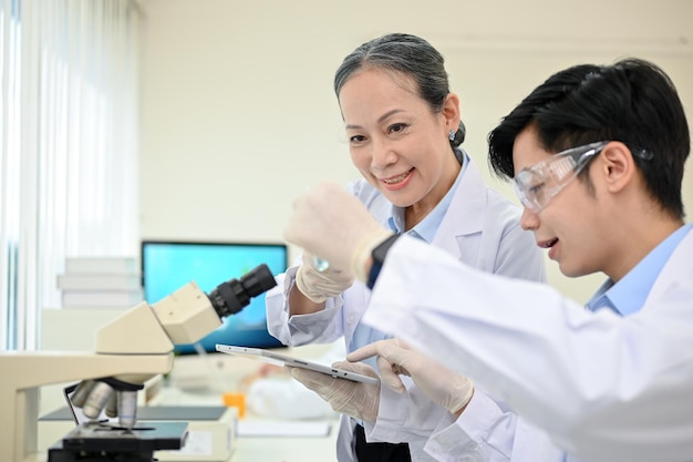 Un talentoso especialista médico o científico masculino asiático que trabaja en el laboratorio con un supervisor senior