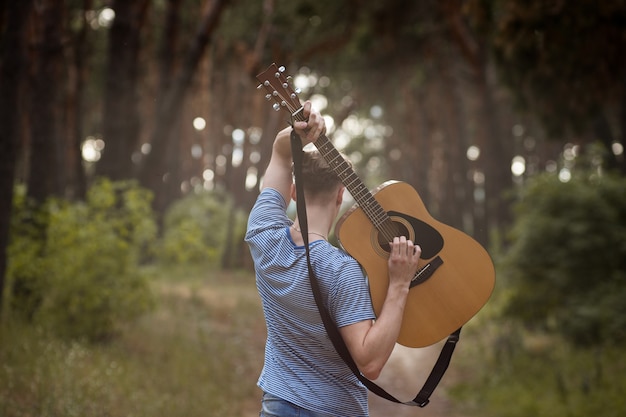 Talentoso guitarrista tocando el concepto de senderismo por el bosque