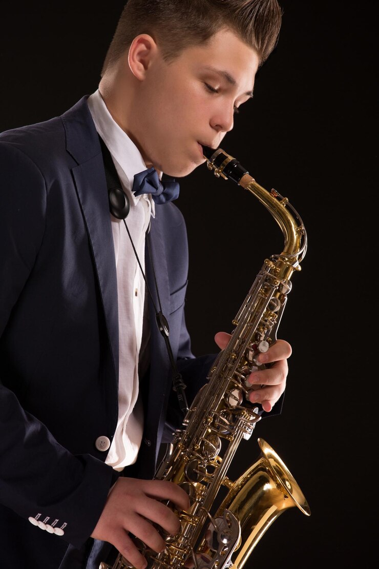 Foto talentoso saxofonista tocando el saxofonista en silueta de estudio. hombre en azul marino aislado en negro.