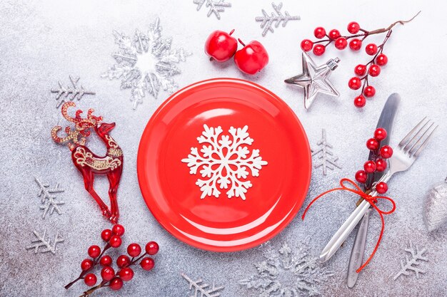 Talheres de mesa de Natal com prato vermelho vazio e talheres com decorações festivas