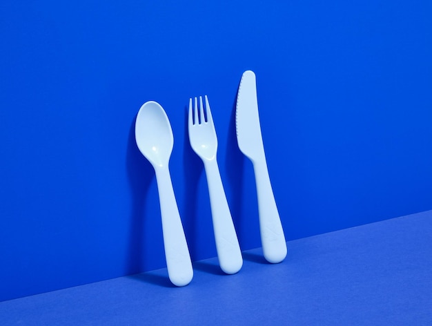 Talheres de plástico sobre um fundo azul Faca garfo colher para comida e deliciosas sobremesas de férias