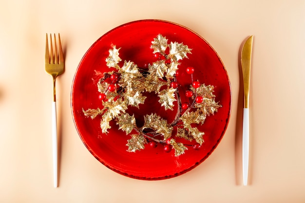 Talheres dourados de fundo de Natal e um prato vazio vermelho sobre um fundo claro servindo