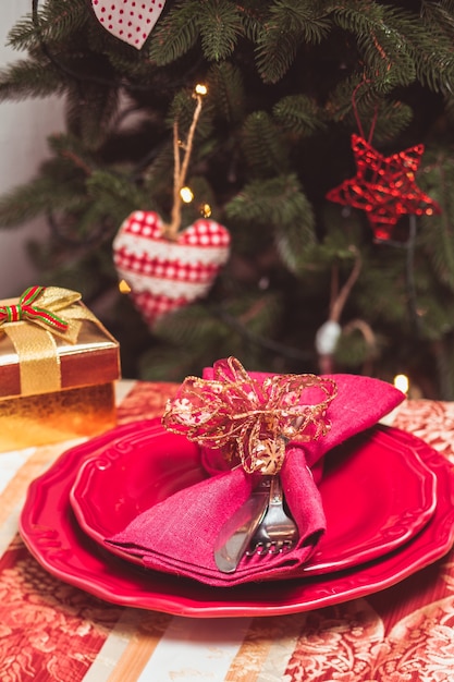 Talheres que se apresentavam em vermelho sobre um fundo da árvore de Natal