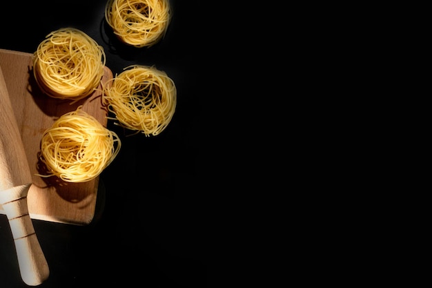 Tallarines enrollados en forma de pasta italiana sobre fondo de piedra negra Foto de alta calidad