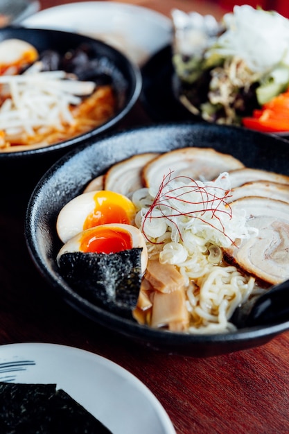Foto tallarines japoneses en sopa de miso con chashu de cerdo, huevo duro, algas secas