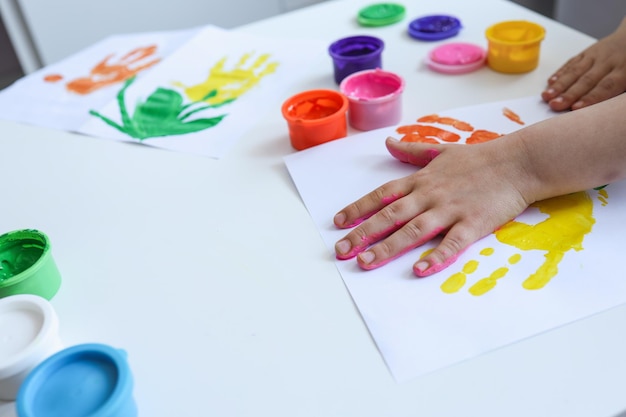 Taller de arte infantil el niño hace una huella de mano con pinturas