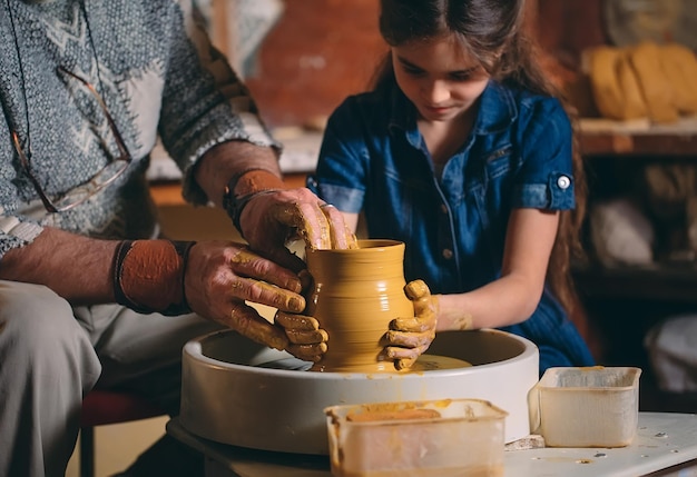 Taller de cerámica. El abuelo le enseña cerámica a la nieta. Modelado en arcilla.