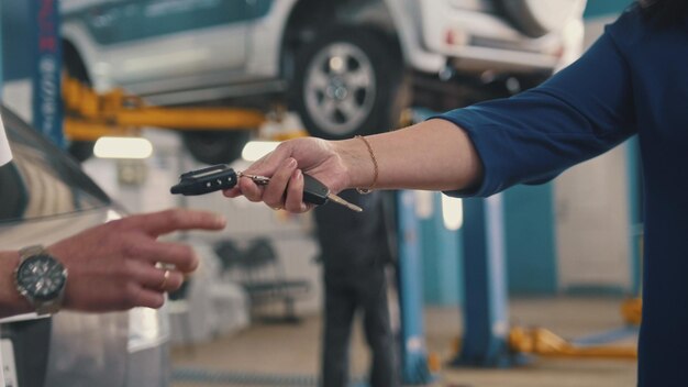 Taller de coches - mujer da las llaves del coche para mecánico, telefoto