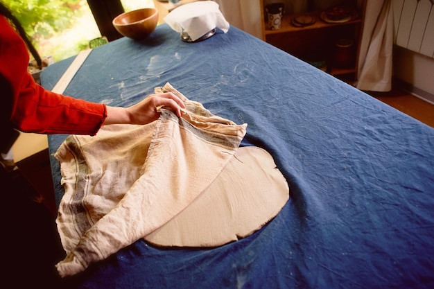 Taller creativo de ceramista Arcilla enrollada bajo un trozo de tela lisa de algodónEl proceso de apertura de la arcilla bajo la tela Flujo de trabajo