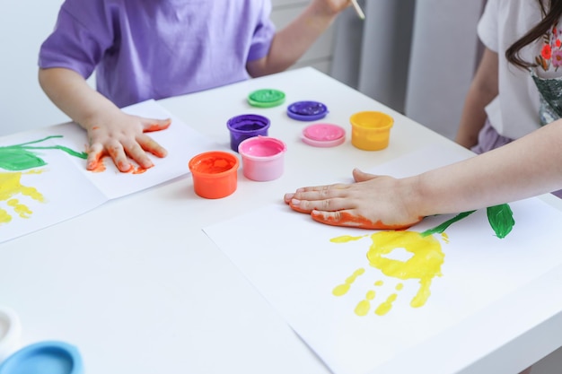 Taller de dibujo infantil niños felices hacen huellas de manos con pintura