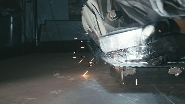 Taller de forja Smithy Worker en un casco de campana de soldadura suelda una pieza mediante soldadura eléctrica Las chispas se reflejan en la pantalla protectora El herrero fabrica productos de hierro para la fabricación Cámara lenta