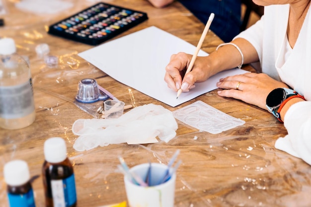 Taller de joyería con resina epoxi Primer plano de las manos de una mujer esbozando ideas