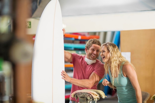 Taller de moldeo de tablas de surf, hombre y mujer felices con tabla de surf