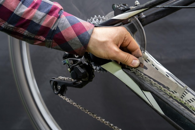 Taller profesional para la reparación y mantenimiento de bicicletas de montaña modernas Manos mecánicas y una herramienta para comprobar el desgaste de la cadena de cierre Reemplazo de la cadena en la bicicleta