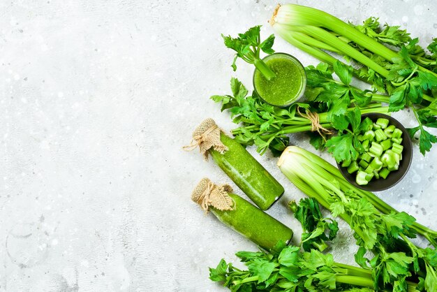 Tallo de apio verde y jugo de apio sobre fondo de piedra gris Bebida vegetariana Espacio libre para texto