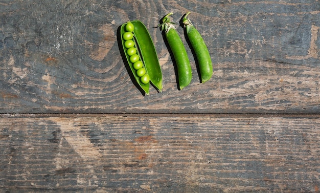 Tallos de guisantes verdes sobre una textura de madera Tableros Cocinar jardinería huerta