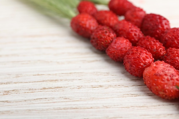 Tallos de hierba con fresas silvestres en primer plano de la mesa de madera blanca Espacio para texto