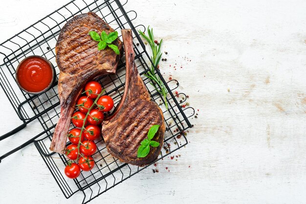 Tamahavk-Steak am Knochen mit Gewürzen und Kräutern auf weißem Holzhintergrund Draufsicht Freier Kopierbereich