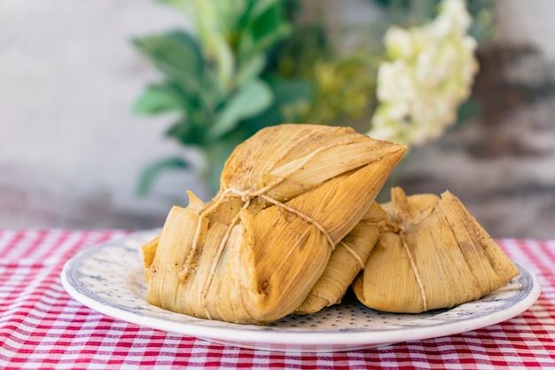 Tamales andinos tradicionais de milho e carne servidos em uma placa de madeira. Comida regional.