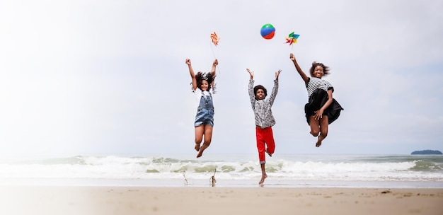 Tamanho da faixa Grupo de crianças afro-americanas felizes pulando em uma praia tropical