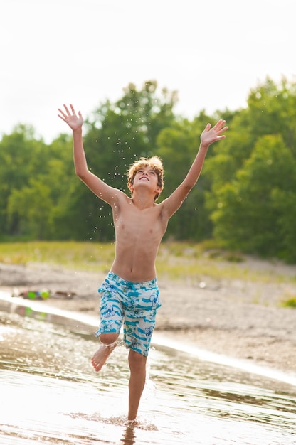 El tamaño completo de un niño sin camisa en la playa