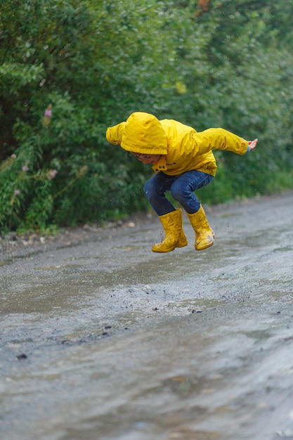 Foto el tamaño completo del niño saltando bajo la lluvia