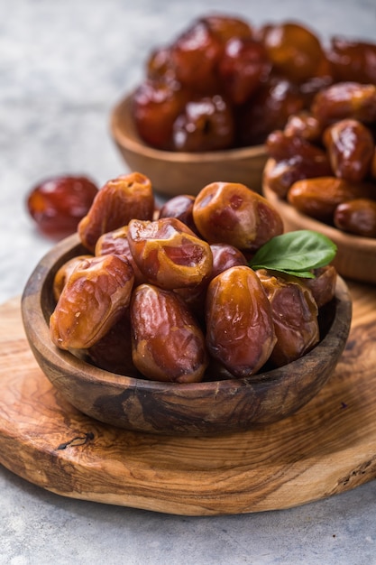 Tâmaras ou dattes de frutas de palma em uma tigela de madeira são lanches saudáveis.