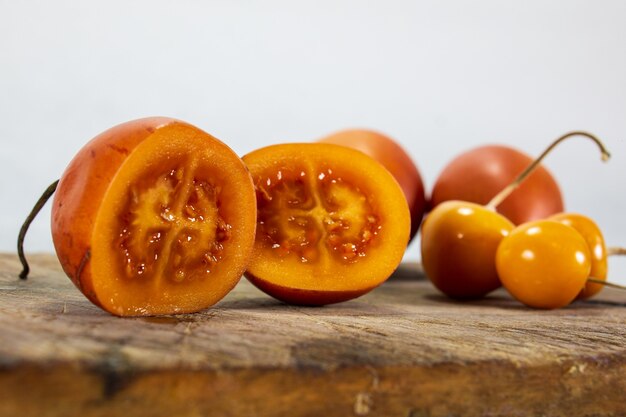 Tamarillo o tomate de árbol sobre tabla de madera junto a uvilla o aguaymanto physalis