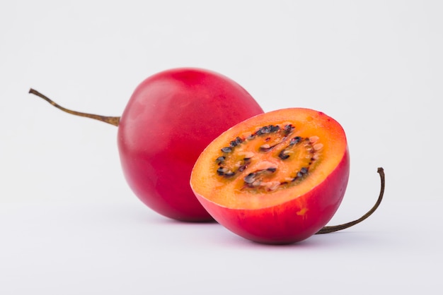 Tamarillo rojo con una rebanada sobre fondo blanco