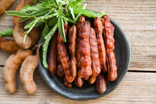 Tamarindo dulce para comida fruta tamarindo maduro en plato y fondo blanco Cáscara de tamarindo en plato frutas tropicales vista superior de verano