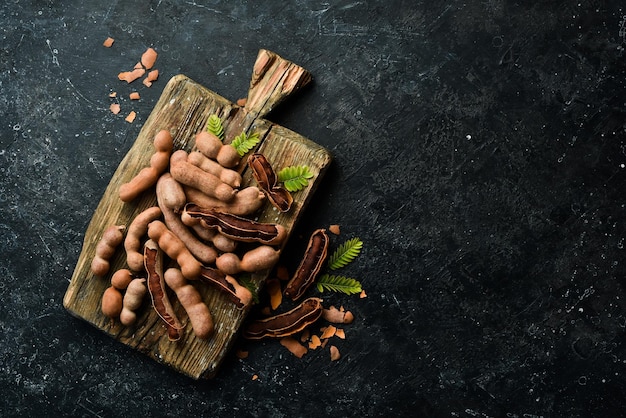 Tamarindo maduro em uma placa de madeira de cozinha Em um fundo de pedra Vista superior