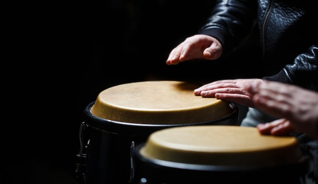 Tambor. mãos de um músico tocando bongos. o músico toca bongô.