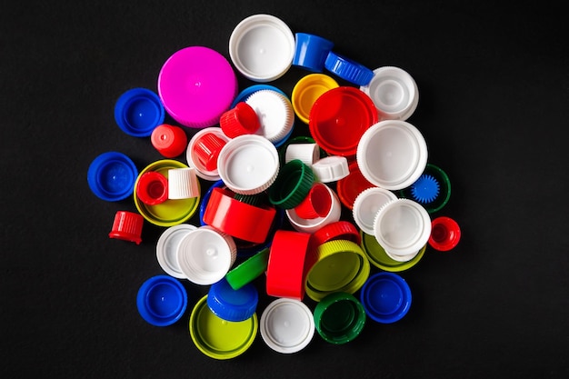 Foto tampas de garrafa de plástico recicladas vista superior de uma pilha de tampas de garrafa de plástico coloridas em fundo preto
