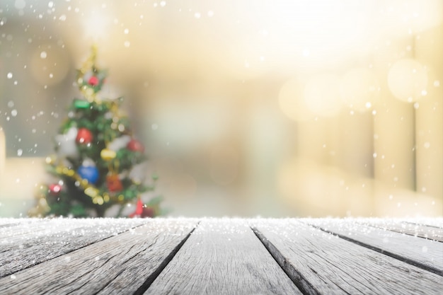 Tampo da mesa de madeira vazio no desfoque com bokeh árvore de Natal e decoração de ano novo no fundo do banner da janela com neve - pode ser usado para exibir ou montar seus produtos.