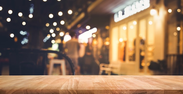 Tampo de mesa de madeira com desfoque de iluminação em um café de rua à noite