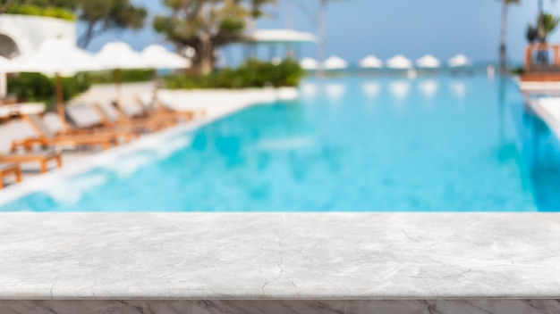 Tampo de mesa de pedra de mármore branco vazio e piscina turva em resort tropical em fundo de banner de verão pode ser usado para exibir ou montar seus produtos