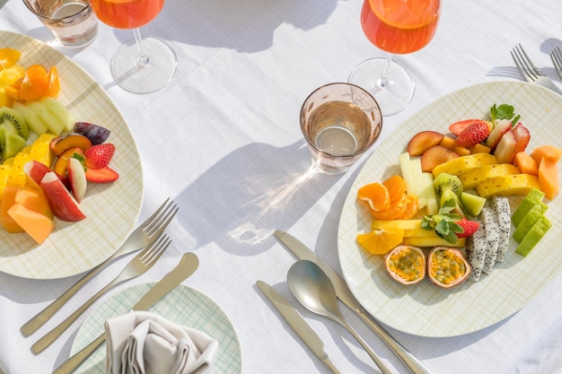 Tampo de mesa elegante, cenário branco com prato de frutas para o café da manhã, salada de frutas. Prato de frutas ensolarado ao ar livre