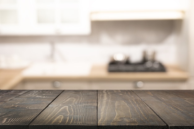 Tampo de mesa em madeira e cozinha moderna desfocada para expor seus produtos. Fundo desfocado da cozinha abstrata.