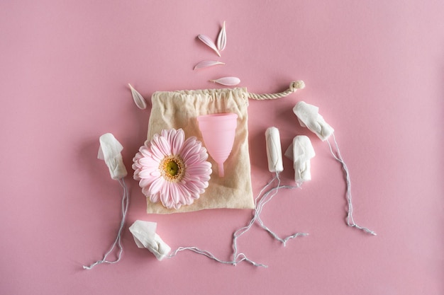 Tampões e copo menstrual em fundo rosa