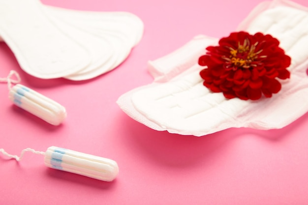 Foto tampões menstruais e almofadas em fundo rosa. uma rosa fica em uma almofada menstrual. ciclo de menstruação. higiene e proteção. vista do topo. foto vertical