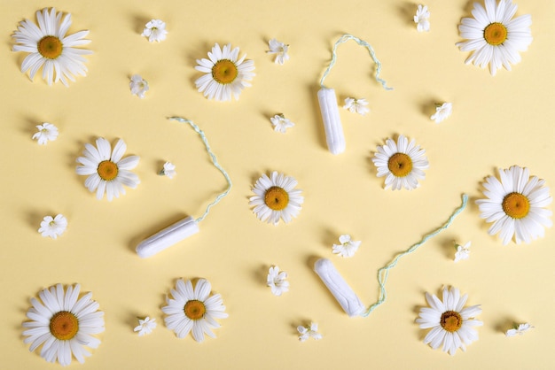 Tampones para mujeres y patrón de manzanilla en flor sobre un fondo beige pastel idea ley plana para la salud de las mujeres