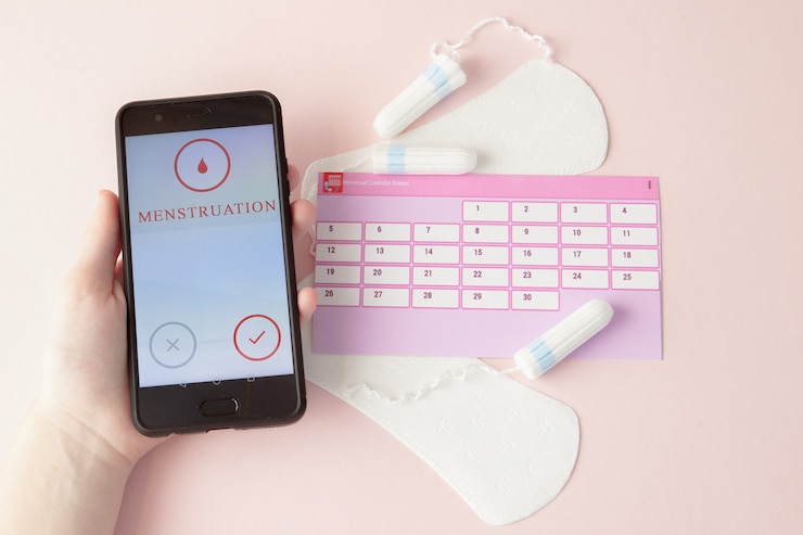 Foto tampones, toallas sanitarias femeninas para días críticos, calendario femenino, pastillas para el dolor durante la menstruación sobre un fondo rosa. seguimiento del ciclo menstrual y la ovulación