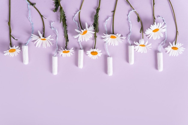 Tampons für Frauen mit einer Blüte von Kamillenblüten auf einem pastelllila Hintergrund, flacher Ley-Kopienraum